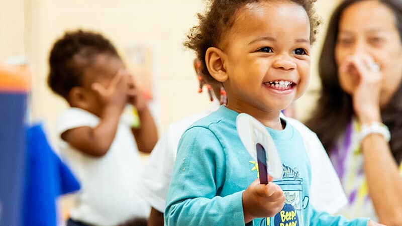 Young child holding a fan and taking part in an activity