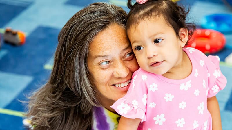 A young child standing close to child care provider