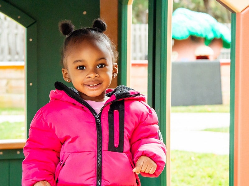 Little girl playing in playhouse outside learning center