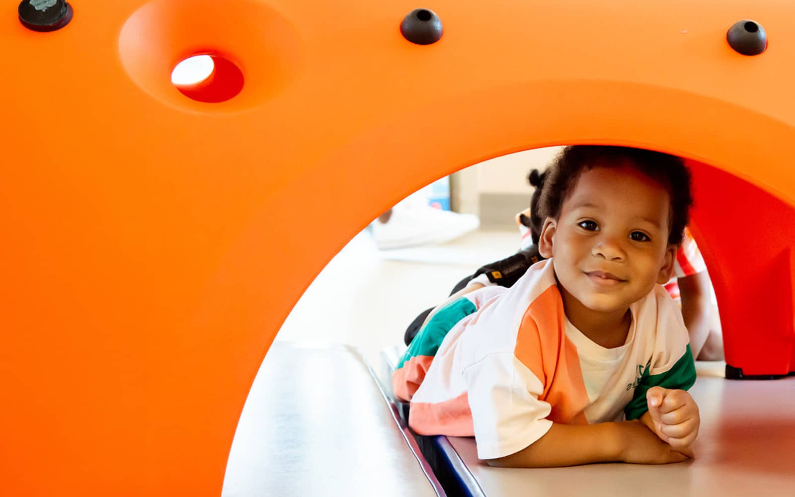 Young child posing under play tunnel