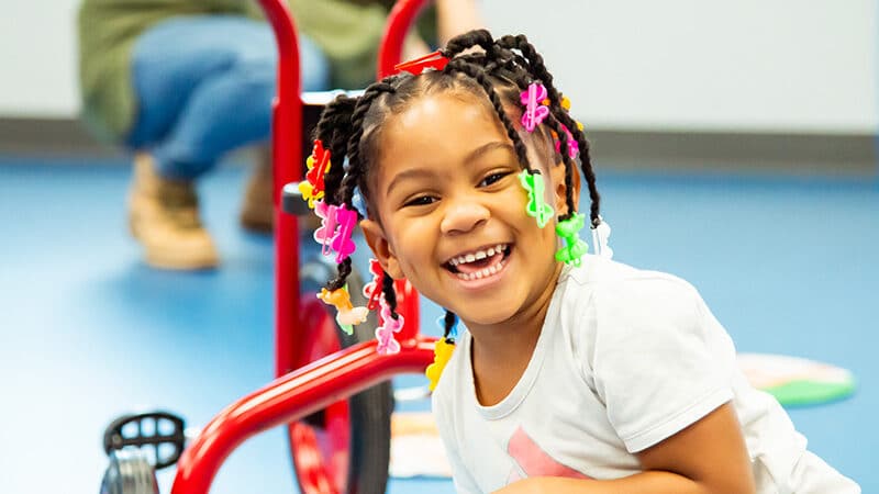 Child posing in front of tricycle