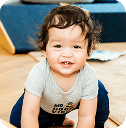 Young child crawling while looking up at the camera
