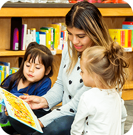 Teacher reading a book to two young children